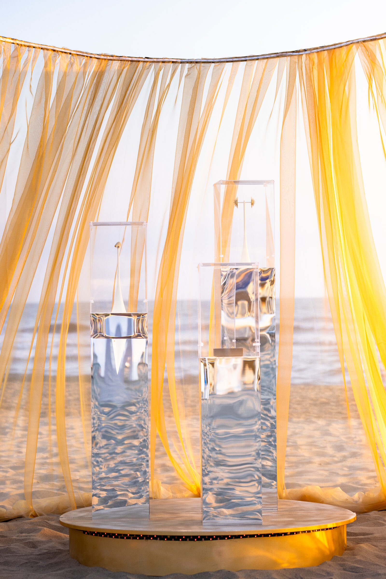 L’allestimento sulla spiaggia, tra tendaggi dorati e teche
